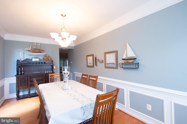 dining space featuring light wood-type flooring, crown molding, and a chandelier