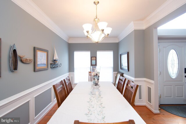 dining area featuring crown molding, a chandelier, and hardwood / wood-style flooring