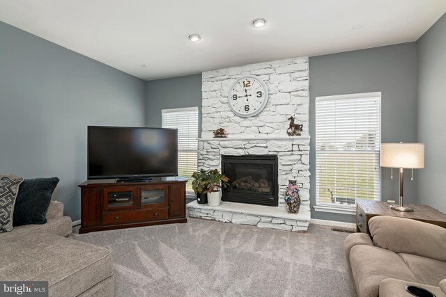 carpeted living room featuring a stone fireplace