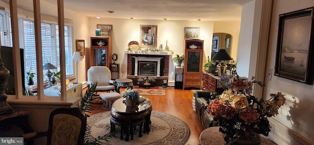 living room featuring a brick fireplace and wood finished floors