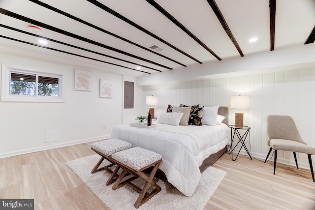 bedroom with electric panel, beam ceiling, and light hardwood / wood-style flooring