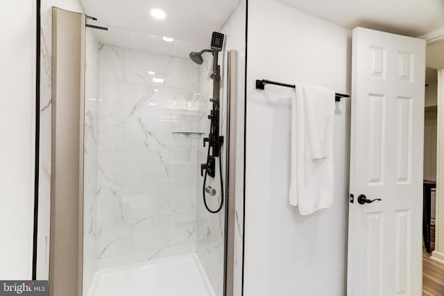 bathroom with wood-type flooring and a tile shower