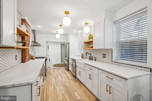 kitchen with wall chimney range hood, backsplash, stainless steel appliances, and white cabinetry