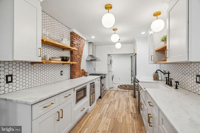 kitchen featuring tasteful backsplash, hanging light fixtures, white cabinets, and wall chimney range hood