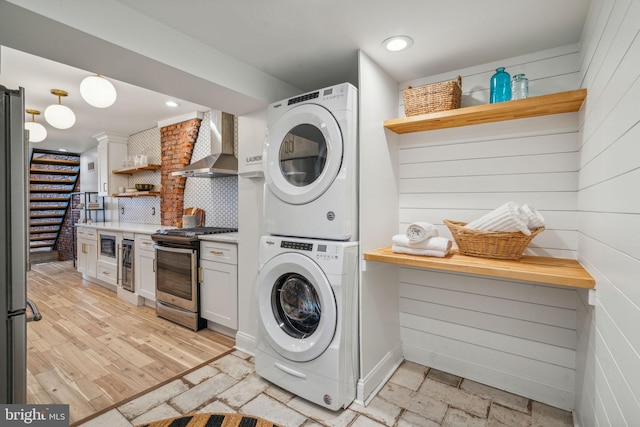 laundry area with light wood-type flooring, stacked washing maching and dryer, and wine cooler