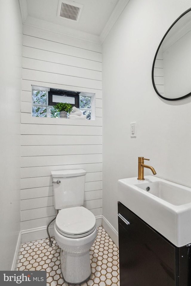 bathroom featuring toilet, tile patterned floors, crown molding, vanity, and wood walls