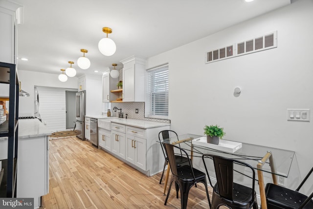 kitchen with light wood-type flooring, white cabinets, light stone counters, and decorative backsplash