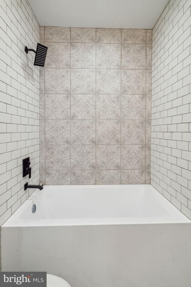 bathroom featuring tiled shower / bath and tile walls