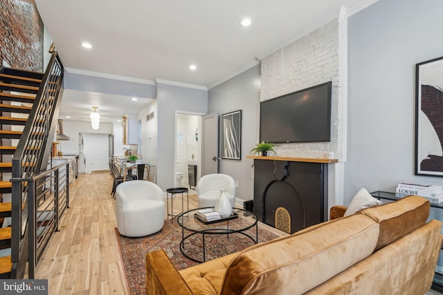 living room featuring a fireplace, crown molding, and light hardwood / wood-style floors