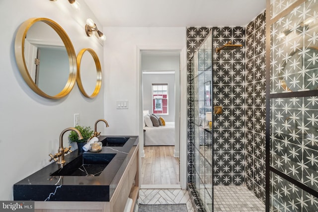 bathroom featuring vanity, a tile shower, and wood-type flooring