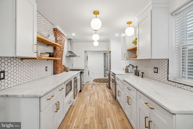 kitchen featuring light wood-type flooring, white cabinetry, backsplash, and wall chimney range hood