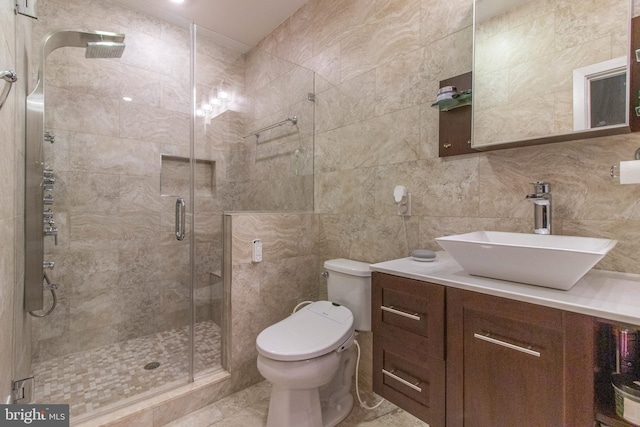 bathroom with tile walls, tile patterned floors, vanity, and a shower with shower door