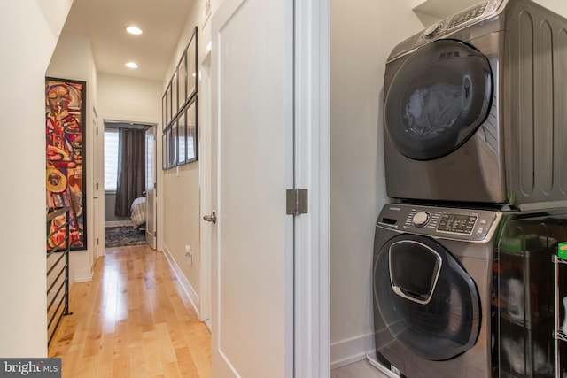 laundry area featuring light wood-type flooring and stacked washer / drying machine