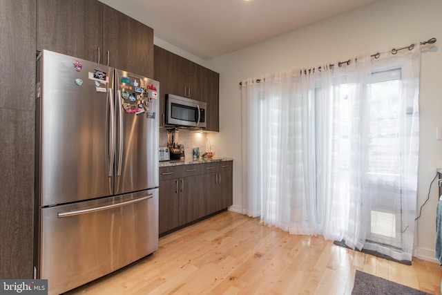 kitchen featuring dark brown cabinets, light wood-type flooring, appliances with stainless steel finishes, and a healthy amount of sunlight