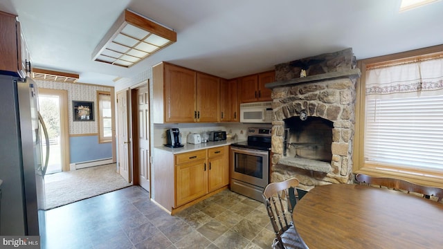 kitchen featuring tile patterned floors, a baseboard heating unit, a stone fireplace, and stainless steel appliances