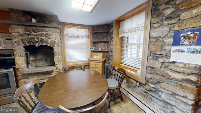 dining area with a fireplace, a baseboard radiator, and tile patterned floors