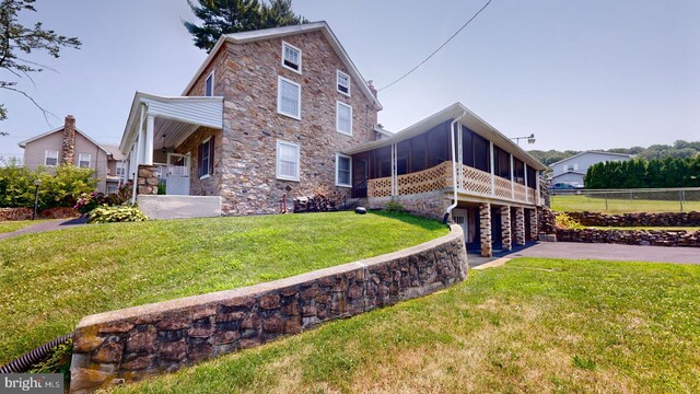 view of property exterior with a sunroom and a lawn