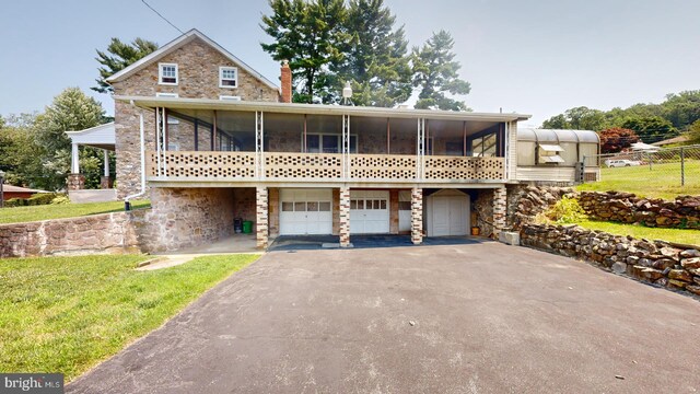 view of front of house with a garage, a front lawn, and a sunroom