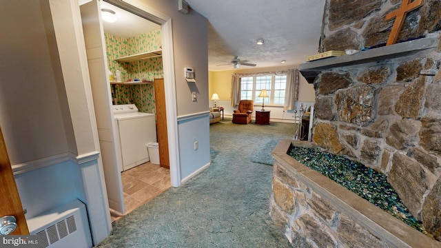 hallway featuring light colored carpet, a textured ceiling, radiator heating unit, and washer / dryer