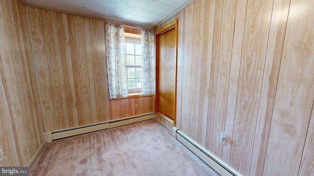 spare room with wood walls, light colored carpet, and baseboard heating