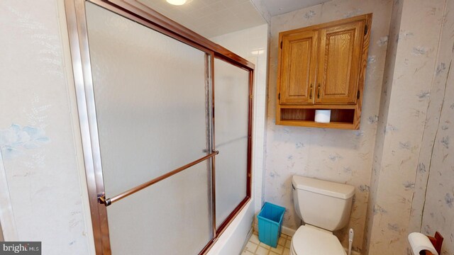 bathroom with shower / bath combination with glass door, toilet, and tile patterned floors