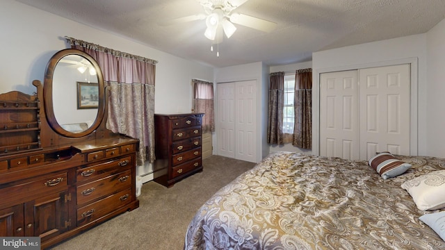 carpeted bedroom with ceiling fan, a textured ceiling, and multiple closets