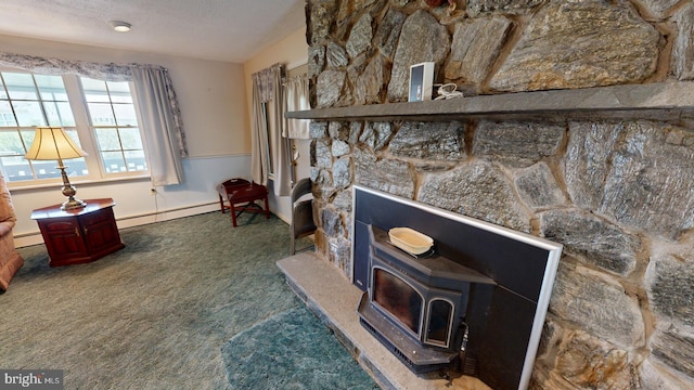 interior space featuring a baseboard heating unit, a wood stove, a textured ceiling, and a fireplace