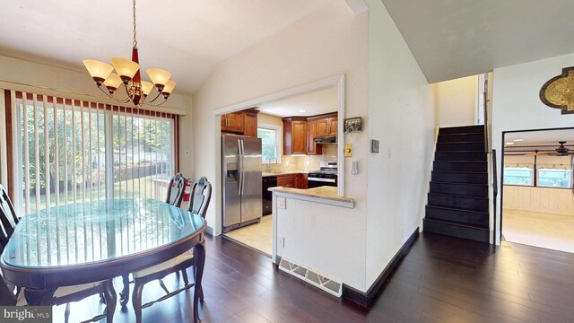 dining area with vaulted ceiling, wood-type flooring, sink, and an inviting chandelier