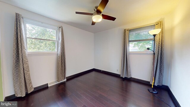 empty room featuring ceiling fan, plenty of natural light, and dark hardwood / wood-style flooring