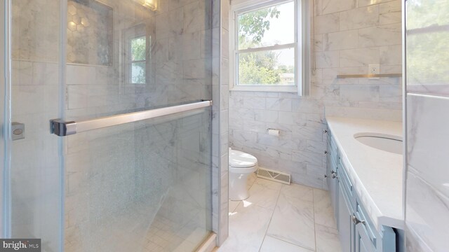 bathroom featuring vanity, tile patterned flooring, a shower with shower door, tile walls, and toilet