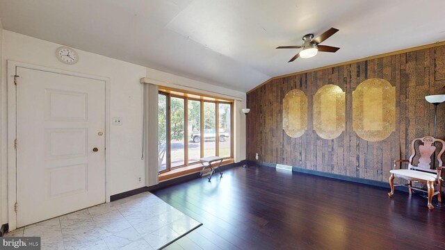 foyer with wood walls, wood-type flooring, ceiling fan, and lofted ceiling