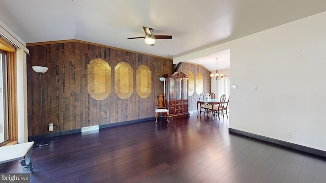 unfurnished room featuring wood walls, ceiling fan with notable chandelier, and wood-type flooring