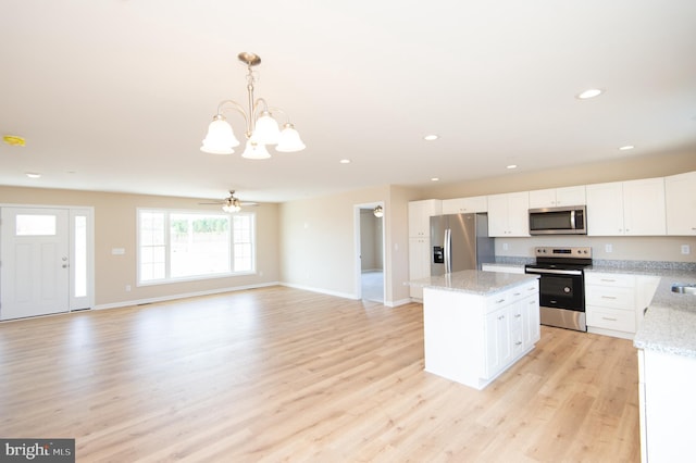 kitchen with white cabinetry, decorative light fixtures, appliances with stainless steel finishes, ceiling fan with notable chandelier, and light wood-type flooring