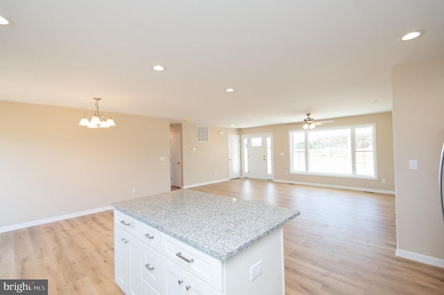 kitchen featuring white cabinetry, hanging light fixtures, light hardwood / wood-style floors, and ceiling fan with notable chandelier