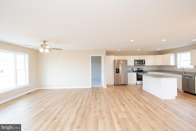 kitchen with white cabinetry, light hardwood / wood-style flooring, a kitchen island, and stainless steel appliances