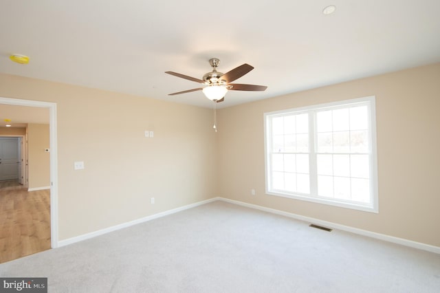 empty room featuring ceiling fan and light carpet