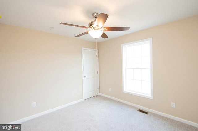 empty room with plenty of natural light, ceiling fan, and light colored carpet