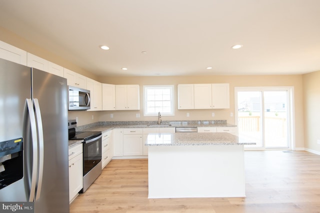 kitchen featuring white cabinets, a center island, stainless steel appliances, and a wealth of natural light