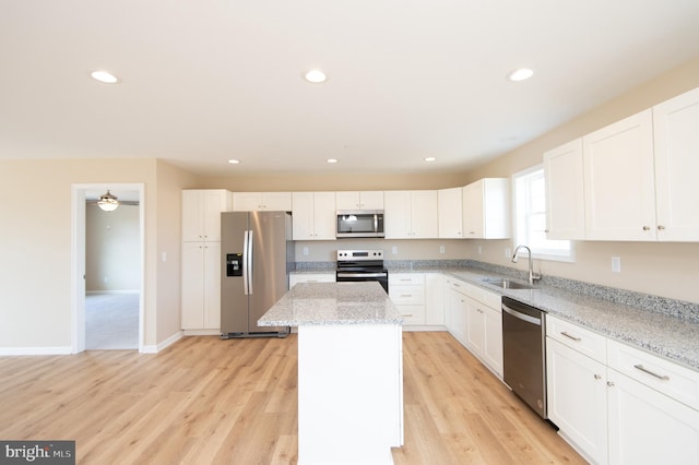 kitchen featuring white cabinets, sink, light stone countertops, a kitchen island, and stainless steel appliances