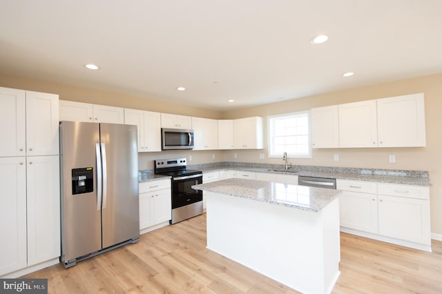 kitchen with light wood-type flooring, a center island, stainless steel appliances, and white cabinetry