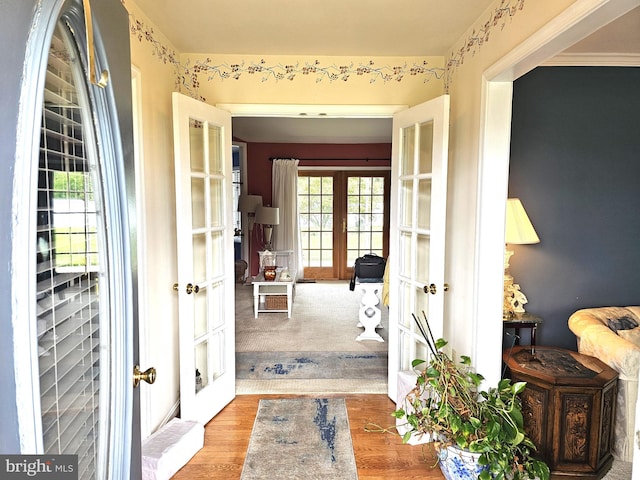 corridor featuring french doors, ornamental molding, and wood-type flooring