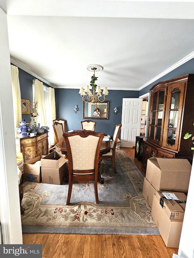 dining room with an inviting chandelier, ornamental molding, and hardwood / wood-style floors