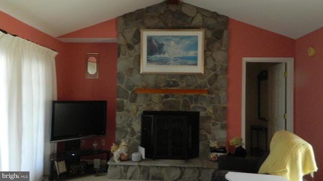 living room with a stone fireplace and vaulted ceiling