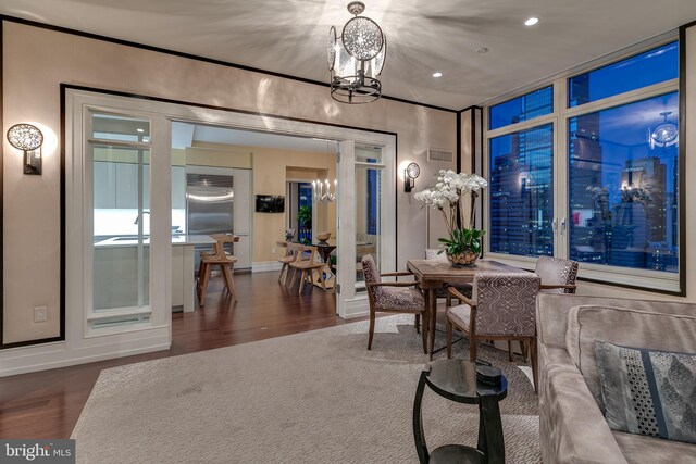 hall featuring a notable chandelier, a raised ceiling, decorative columns, and parquet flooring