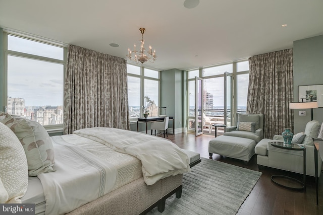 bedroom featuring dark wood-style floors, a city view, a notable chandelier, and multiple windows