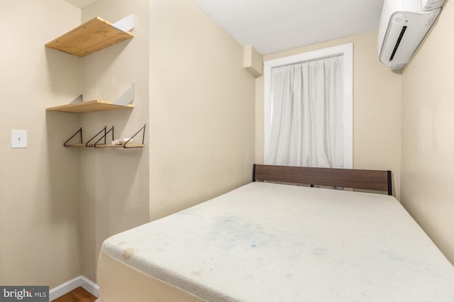 bedroom with hardwood / wood-style floors and a wall unit AC