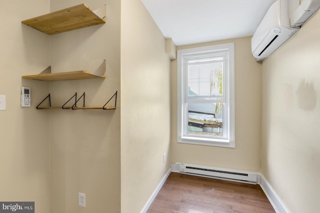 interior space with hardwood / wood-style floors, baseboard heating, and a wall unit AC