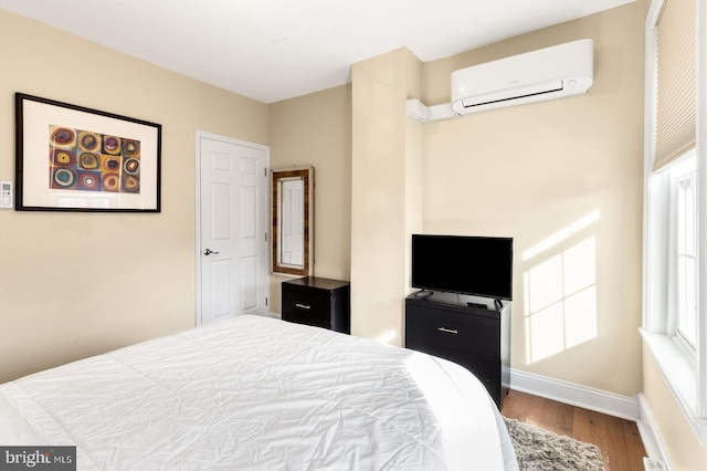 bedroom with wood-type flooring and a wall mounted AC