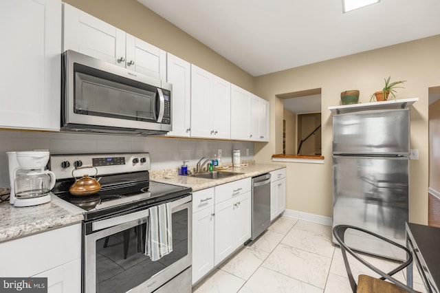 kitchen with tasteful backsplash, sink, stainless steel appliances, and white cabinets