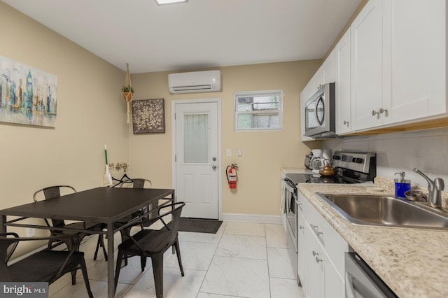 kitchen with a wall mounted air conditioner, appliances with stainless steel finishes, sink, light tile patterned floors, and decorative backsplash